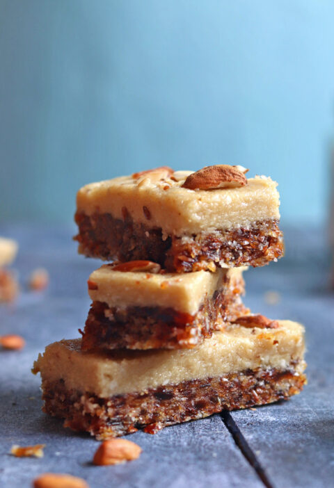 Dates and Coconut Energy Bars with almonds on top over a blue backdrop