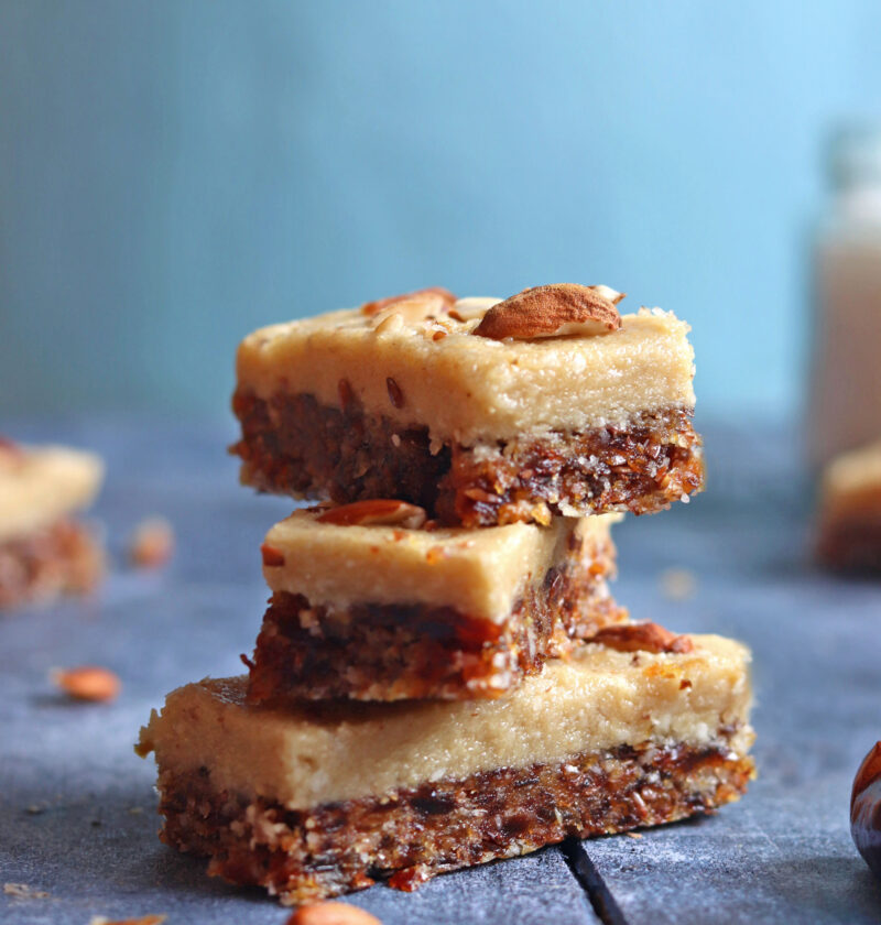 Dates and Coconut Energy Bars with almonds on top over a blue backdrop