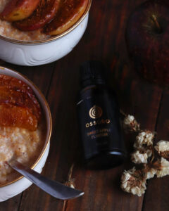 Apple Cinnamon Breakfast Porridge served in a white bowl on a wooden table with an Ossoro sweet apple flavour bottle