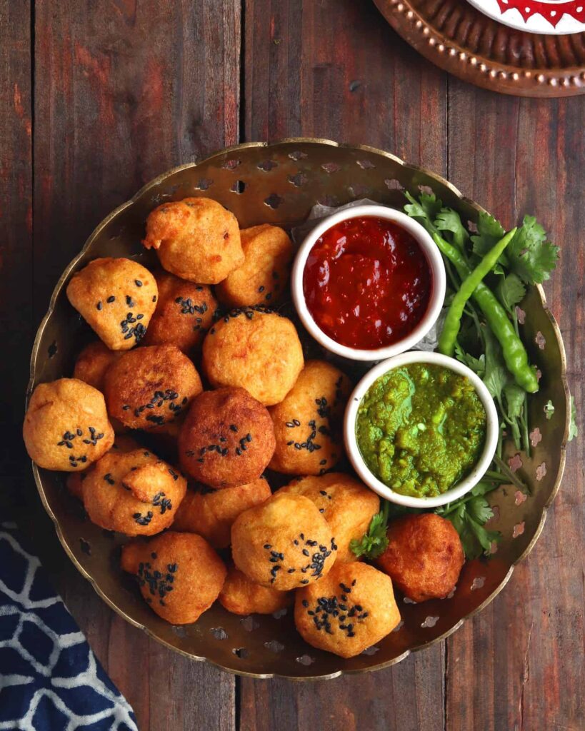 Urad Dal Vada on a copper bowl over a wooden table served with green and red chutney