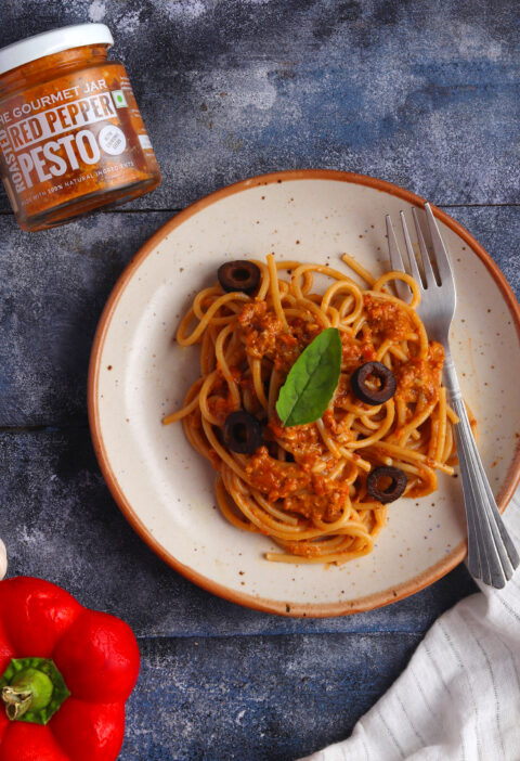 Red Pepper Pesto Spaghetti on a white plate over a blue table
