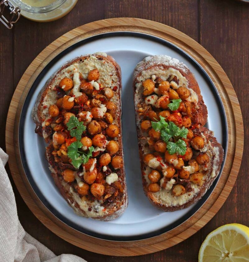 Chickpea Tahini Toast on a white plate over a wooden surface
