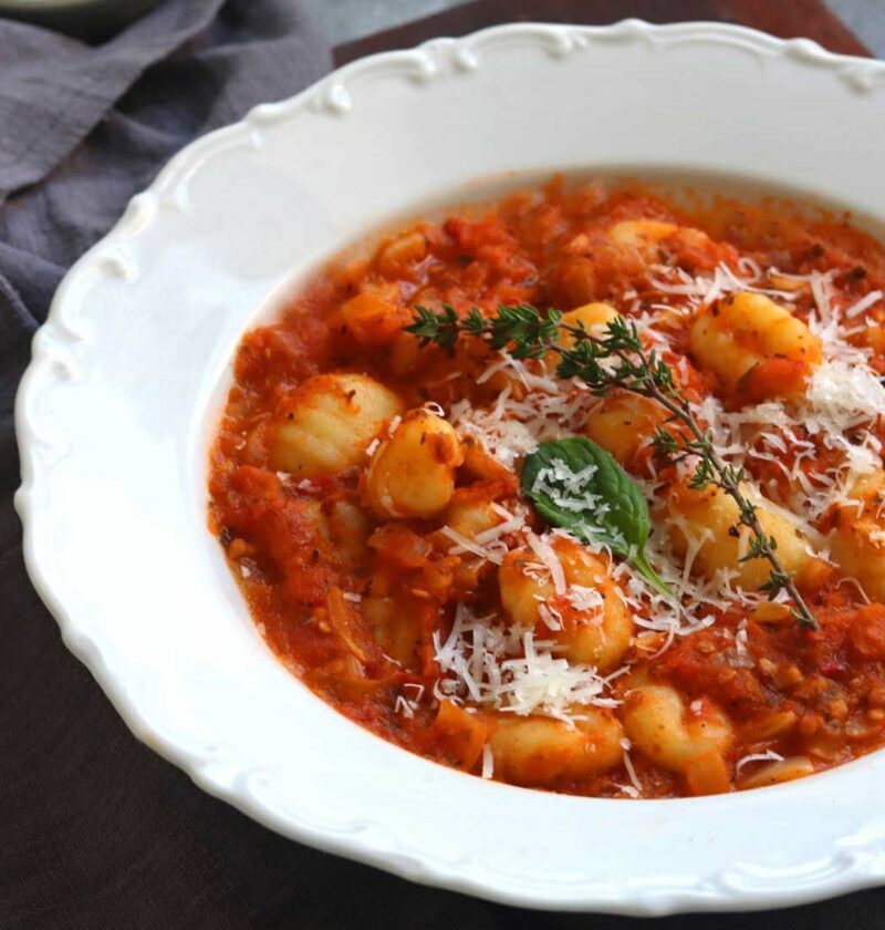 Gnocchi with Tomato Sauce in a white saucer with parmesan cheese