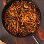 Garlic Mushroom Noodles in a black frying pan on a wooden table