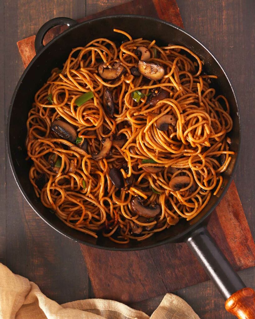 Garlic Mushroom Noodles in a black frying pan on a wooden table
