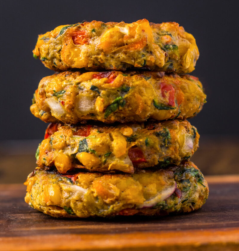 Vegan Corn Fritters stacked on a wooden table