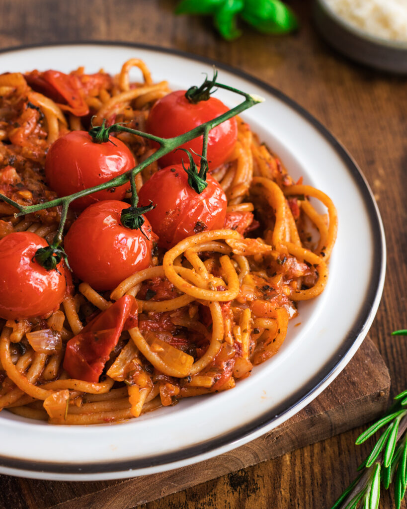 Roasted Cherry Tomatoes Pasta on a white plate over a wooden table