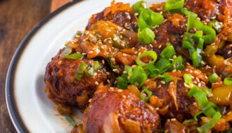 Dry Manchurian on a white plate planes on a wooden table