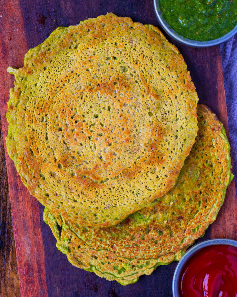 Matar Cheela Recipe on a wooden platter with green chutney and ketchup